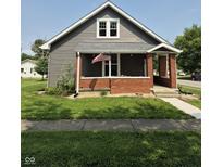 Charming gray home with a cozy front porch, brick accents, and an American flag at 1501 California St, Columbus, IN 47201