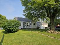 Charming single-story home with a well-maintained lawn, mature trees, and a detached two-car garage at 1510 Chester St, Anderson, IN 46012