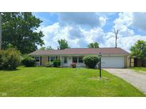 Charming single-story home with a well-manicured lawn, attached garage, and inviting front entrance at 1543 W 79Th St, Indianapolis, IN 46260