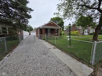 Charming brick home featuring a gated driveway and a well-manicured front yard at 2411 Harlan St, Indianapolis, IN 46203