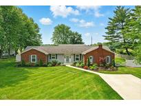 Charming brick and vinyl home with lush front yard, colorful flowers and paved driveway at 3905 E 550 S, Lebanon, IN 46052
