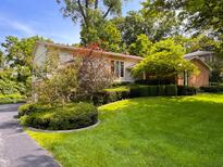 A well-maintained lawn and garden surrounds this charming home's exterior, complete with mature trees at 7038 E 65Th St, Indianapolis, IN 46256