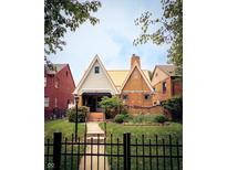 Charming brick home with a peaked roof, manicured lawn, and black wrought iron fence at 972 N Audubon Rd, Indianapolis, IN 46219