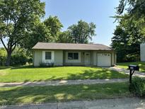 Charming single-story home with well-manicured lawn, mature trees, and an attached single car garage at 1219 Lansdowne Rd, Indianapolis, IN 46234