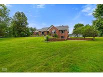 Brick home featuring a large yard, well-maintained landscaping, and basketball hoop at 12196 N Beth Ann Dr, Camby, IN 46113
