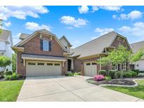 Beautiful brick home with a well-manicured lawn, a three-car garage, and a landscaped front yard with blooming flowers at 1457 Birdsong Dr, Westfield, IN 46074