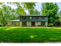 Charming two-story home featuring a stone facade, lush green lawn, and mature trees at 3715 Rolling Springs Dr, Carmel, IN 46033