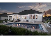 Inviting in-ground pool and outdoor entertaining space with string lights at dusk at 3821 Shady Lake Dr, Westfield, IN 46074