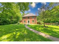 Charming brick two-story home with mature trees and a well-manicured lawn. The house has a walkway and multiple windows at 6125 N Olney St, Indianapolis, IN 46220