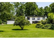 An exterior view of a modern home with a white facade, black trim and verdant lawns and landscaping at 6164 Afton Crest, Indianapolis, IN 46220