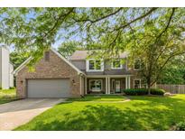 Charming two-story home featuring a brick facade, attached garage, and a well-maintained lawn with mature trees at 6683 Manchester Dr, Fishers, IN 46038
