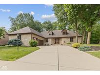 Charming brick home featuring a well-manicured lawn, mature trees and an expansive driveway at 7612 Freedom Woods Dr, Indianapolis, IN 46259