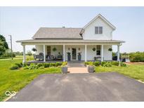 Charming home featuring a large front porch, lush landscaping, and well-maintained lawn at 7728 W 200 S, New Palestine, IN 46163