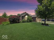 Charming brick home with a well-manicured lawn and mature landscaping at sunset at 8144 Grassy Meadow Cir, Indianapolis, IN 46259
