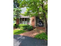 Charming home featuring a brick facade, striped awning, and landscaped garden leading to the front door at 9229 Tamarack Dr, Indianapolis, IN 46260