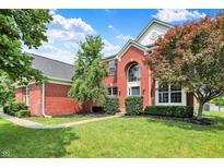 Charming two-story red brick home featuring a well-manicured lawn and mature trees under a bright blue sky at 12635 Tuscany Blvd, Carmel, IN 46032