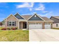 Charming single-story home with a well-manicured lawn, three-car garage and beautiful blue and brown accents at 1758 Pelham Dr, Greenwood, IN 46143