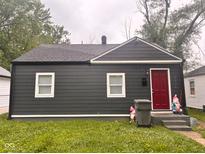 Charming bungalow-style home featuring dark gray siding and a bright red front door at 2954 N Drexel Ave, Indianapolis, IN 46218