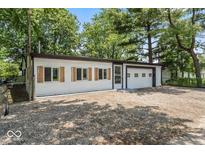 Exterior of home with vinyl siding and garage door nestled amongst mature trees and gravel driveway at 3529 Hunt St, Plainfield, IN 46168