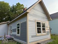 This exterior shot shows a light colored house featuring new windows and light trim at 827 W 9Th St, Anderson, IN 46016