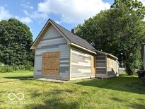 Exterior view of a one-story home featuring light-colored siding and black shingle roof at 827 W 9Th St, Anderson, IN 46016