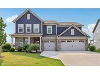 Inviting two-story home boasts a three-car garage, manicured lawn, and classic blue siding at 9671 Ridgecrest Ln, McCordsville, IN 46055