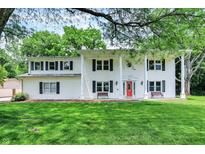 Charming two-story home with a large front yard, white siding and a bright red front door at 1000 Leisure Ln, Greenwood, IN 46142