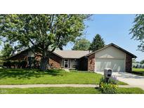 Charming brick home with a two-car garage, lush green lawn, and mature shade tree on a sunny day at 1008 Whispering Trl, Greenfield, IN 46140