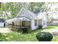 Quaint home features a covered front porch and lush, mature trees in the front yard at 26098 Six Points Rd, Sheridan, IN 46069