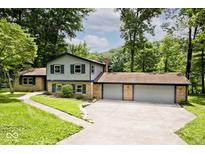 Two-story home with brick accents and a three-car garage surrounded by lush greenery at 3545 Whippoorwill Lake N Dr, Monrovia, IN 46157
