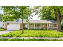 Charming ranch-style home featuring an attached garage, a front porch, and mature landscaping at 48 Wilson Dr, Carmel, IN 46032
