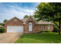 Charming brick home with a well-manicured lawn, an arched entryway, and an attached two-car garage at 5032 Monticello Dr, Columbus, IN 47203