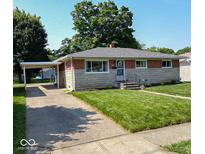 Charming ranch-style home featuring a brick and stone facade, a carport, and a well-manicured lawn at 5609 Meadowood Dr, Indianapolis, IN 46224