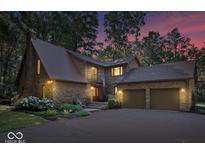 Charming stone home boasts a two-car garage, beautiful landscaping, and a welcoming entrance with an American flag at 6975 Milhouse Rd, Indianapolis, IN 46221