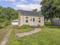 Charming yellow home featuring a well-maintained lawn, walkway, and a detached garage at 2018 N Rochester Ave, Indianapolis, IN 46222