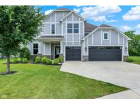 Charming two-story home with a manicured lawn, gray siding and a large driveway leading to an attached two-car garage at 2074 Tompkins Dr, Westfield, IN 46074