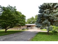 Charming single-story home with a brick exterior, mature trees, and a paved driveway at 7150 Combs Rd, Indianapolis, IN 46237