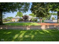 Charming single-story brick home with a beautiful lawn, mature trees, and a circular driveway at 9420 N Kenwood Ave, Indianapolis, IN 46260