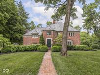 Charming two-story brick home featuring mature trees and professional landscaping along the front yard and walkway at 1207 Pickwick Pl, Indianapolis, IN 46208