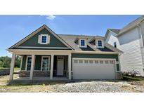 Charming green home boasts a stone-accented facade and a convenient two-car garage, offering curb appeal and practicality at 14277 Coyote Rdg, Noblesville, IN 46060