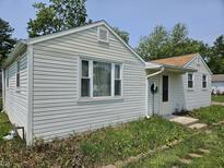 Home exterior features vinyl siding, windows, front door, and a lawn that needs maintenance at 1601 S Biltmore Ave, Muncie, IN 47302