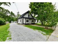 Charming home featuring a gravel driveway, contrasting black and white color scheme, and mature trees at 2801 E Southport Rd, Indianapolis, IN 46227