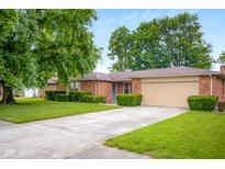 Charming brick ranch home with a well-maintained front yard, mature trees, and a two-car garage at 3235 Flintwood Dr, Columbus, IN 47203