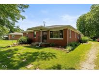 Quaint brick home featuring a charming front porch and beautifully landscaped front yard at 5719 N Frontage Rd, Fairland, IN 46126