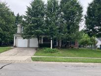 Charming two-story home featuring a well-maintained front yard with mature trees and a two car garage at 7667 Madden Ln, Fishers, IN 46038