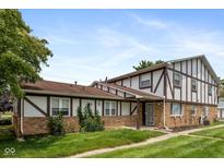 Charming townhome featuring a well-manicured lawn, brick accents, and a welcoming front porch at 10016 Penrith Dr, Indianapolis, IN 46229