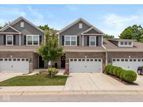 Charming townhome featuring a brick facade, attached garage, and well-manicured lawn at 14442 Treasure Creek Ln, Fishers, IN 46038