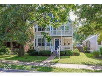 Charming two-story home features a welcoming front porch, balcony, and lush greenery, perfect for suburban living at 2325 N Talbott St, Indianapolis, IN 46205