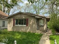 Cozy single-story home featuring a textured facade, large windows, and classic shutters surrounded by mature trees at 3320 E 26Th St, Indianapolis, IN 46218