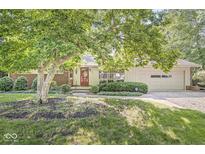 Charming home featuring a brick facade, lush landscaping, and a two-car attached garage at 5841 N Parker Ave, Indianapolis, IN 46220